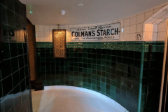 Mixed shades of emerald 6"x6" tiles with tulip border and dado. 6"x6" aged craquelle engobe tiles above