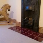 Glossy red ceramic hearth tiles laid in front of a decorative cast-iron fireplace, forming the fireplace hearth.